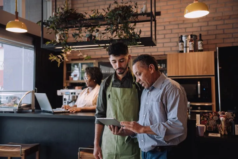 Manager and employee reviewing workforce scheduling on a tablet in a modern workplace, WorkEasy Software for every industry
